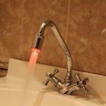 Струя из горячего крана с красным индикатором бежит в раковину